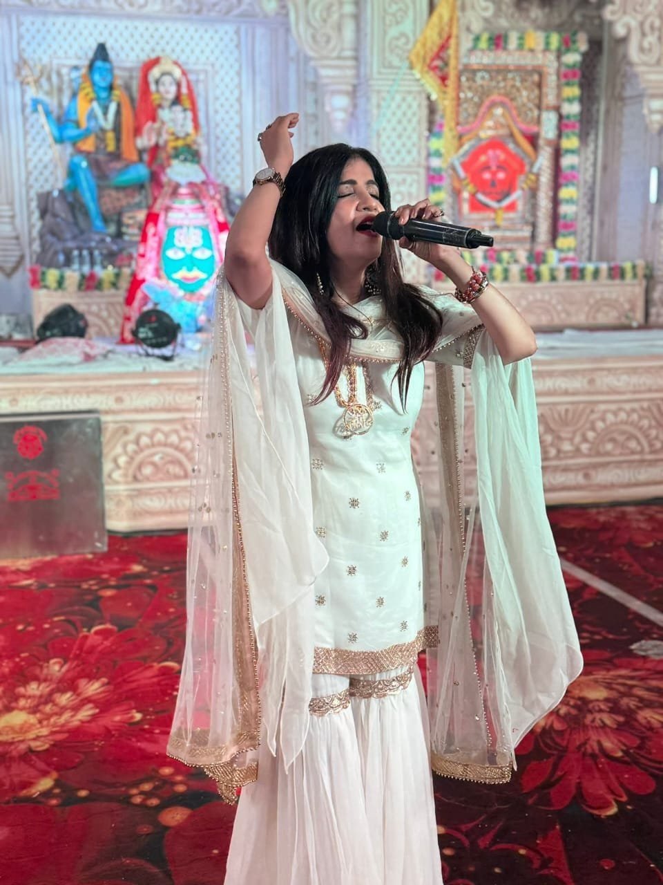 Female devotional singer performing before Shiva and Parvati idols at a temple darbar