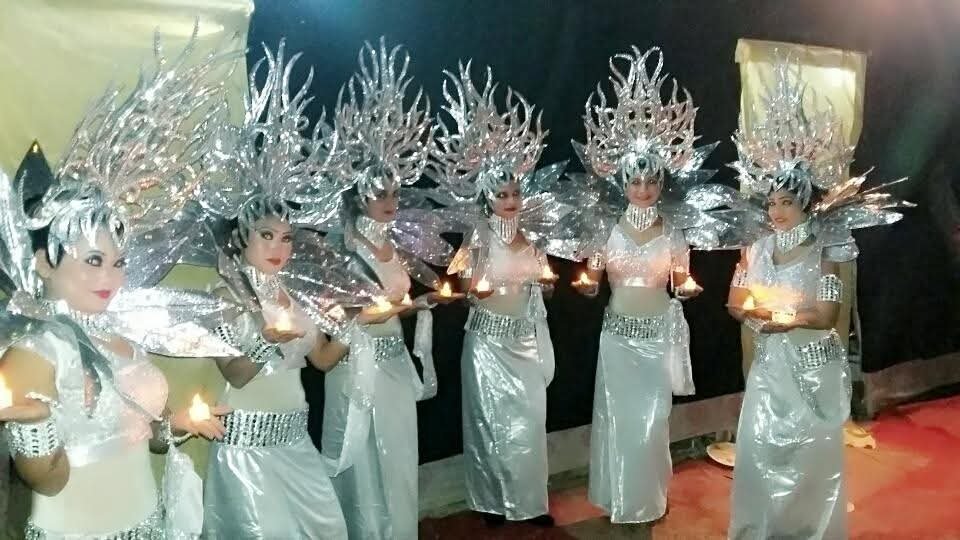 Costumed welcome troupe in silver winged outfits holding lamps for a grand wedding entry