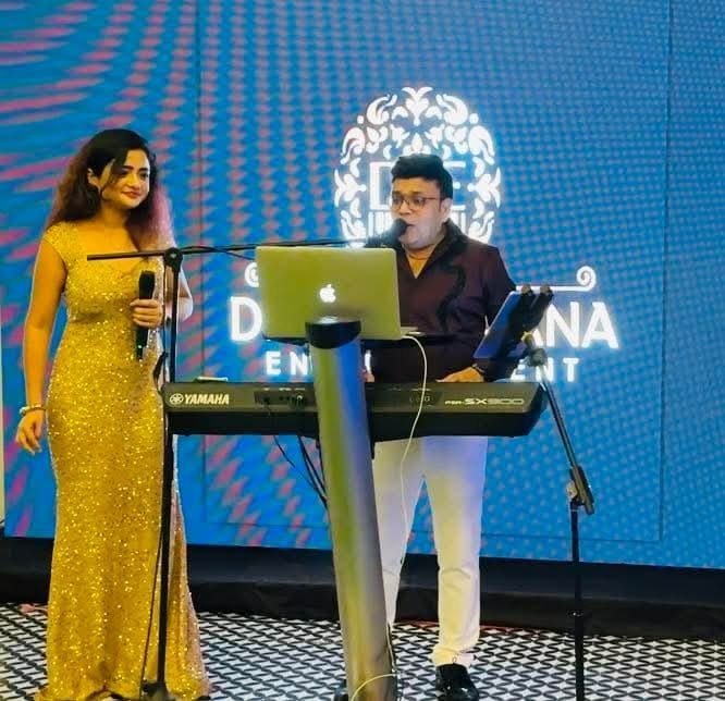 Female vocalist and keyboard player performing together on an LED-lit event stage