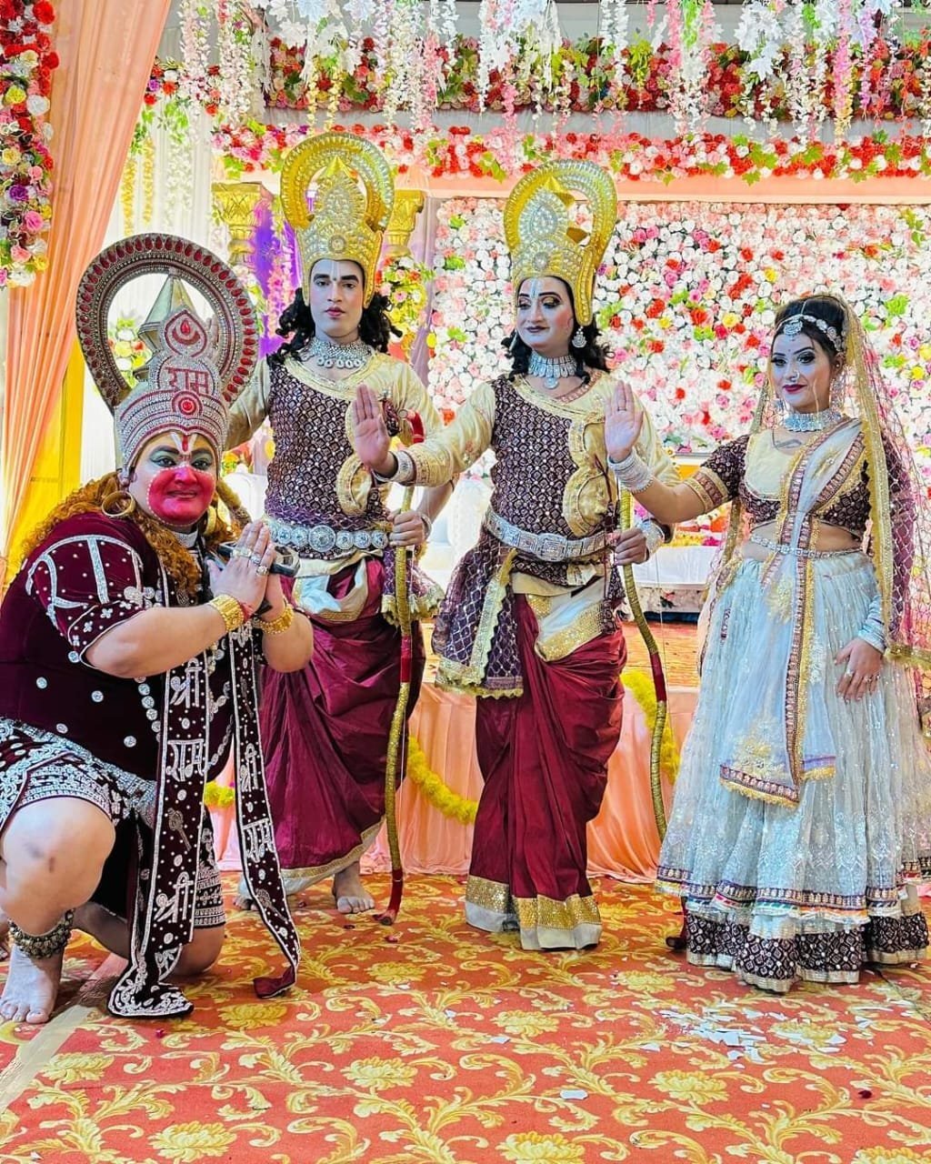Costumed Ram Darbar jhanki tableau with Hanuman, Ram, Lakshman and Sita before a floral backdrop